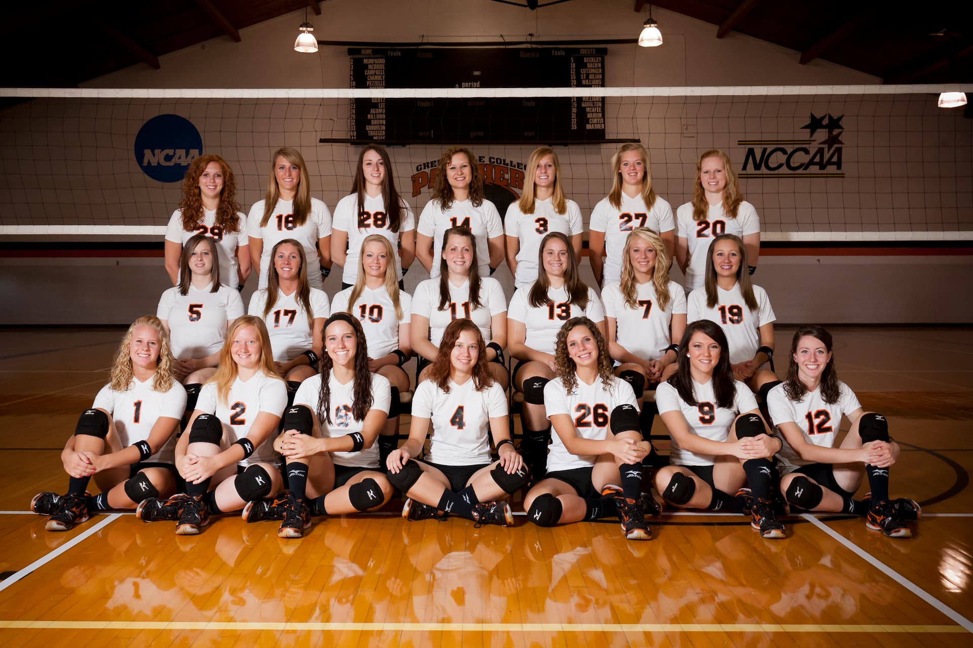 Greenville College women's volleyball team in white shirts arranged in rows in front of the net.