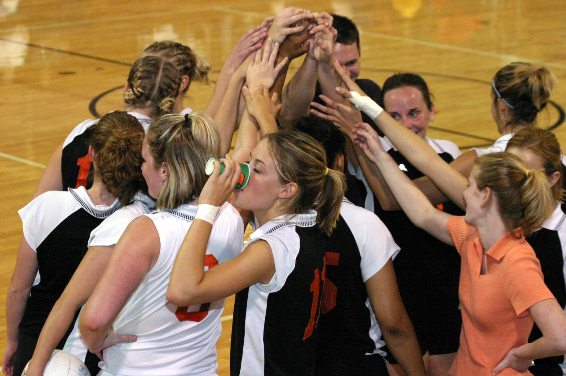 Greenville Panthers volleyball players stacking their hands together in a celebratory huddle.